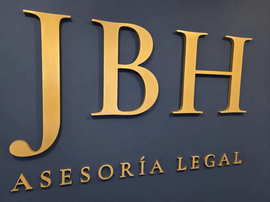 Detalle del logotipo: las letras JBH en dorado en relieve sobre azul marino