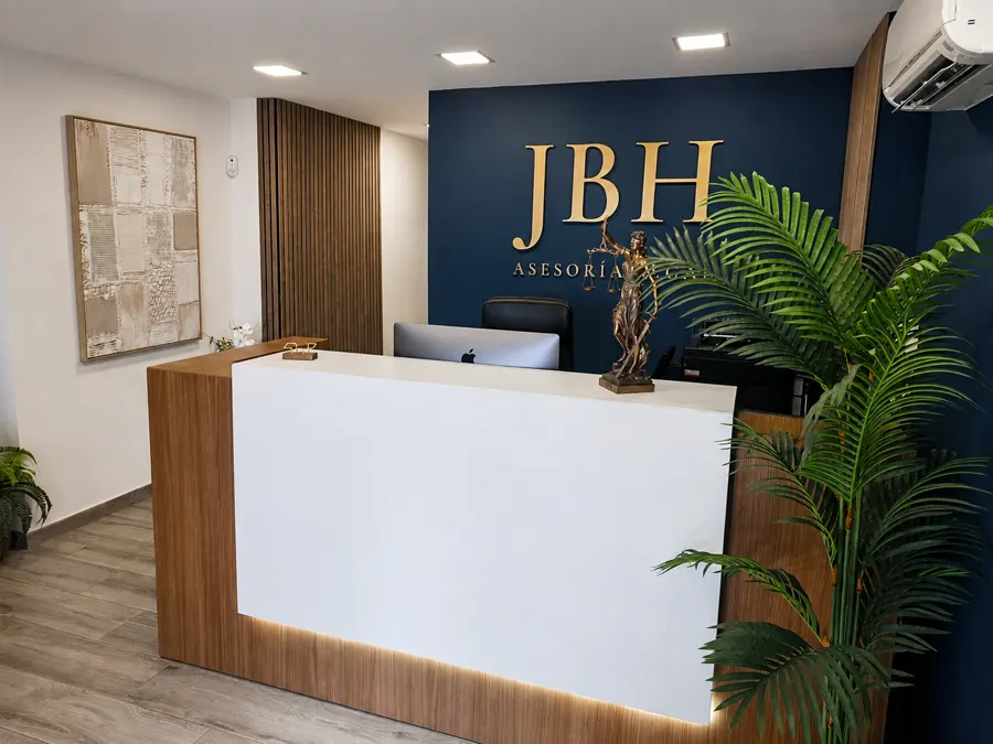 Recepción: mostrador de madera y encimera clara bajo el logotipo dorado sobre pared azul