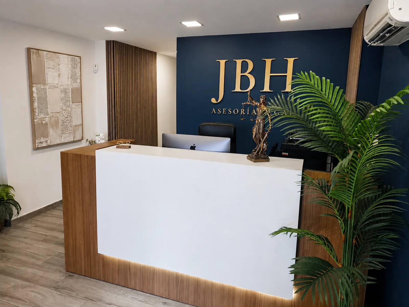 Recepción de JBH, con el mostrador y el logotipo dorado sobre la pared azul